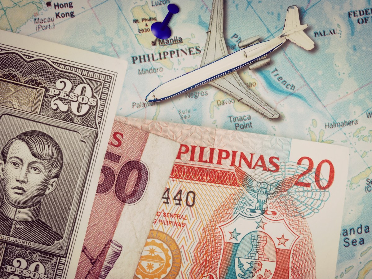 Conceptual image of Filipino paper currency on top of a color map of the Philippines, with a small airplane figurine