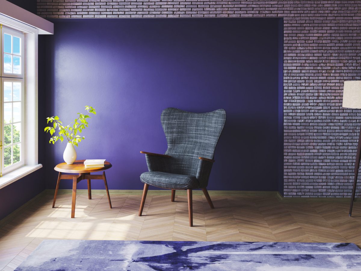 An empty chair sits in a room against a purple wall