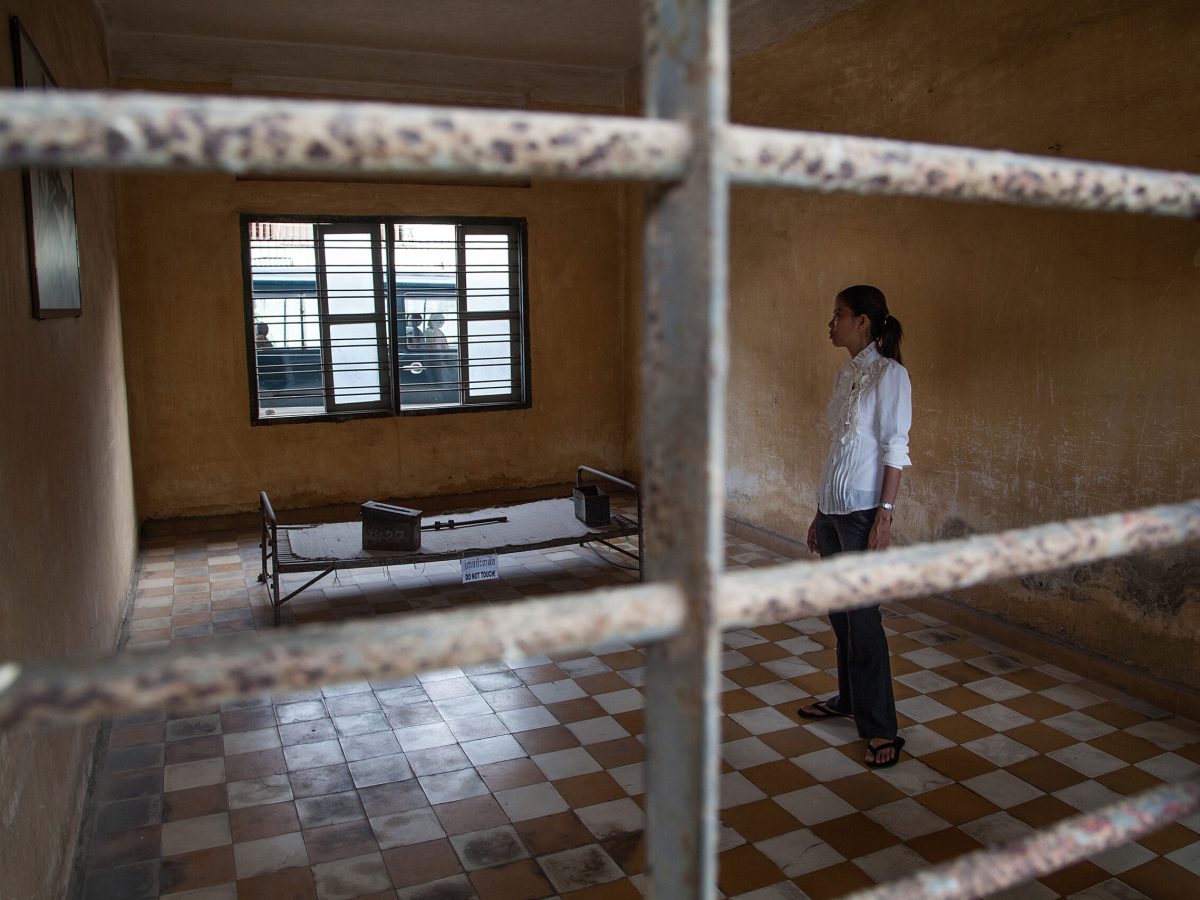 A young Cambodian woman stands in one of the torture rooms of Tuol Sleng prison.