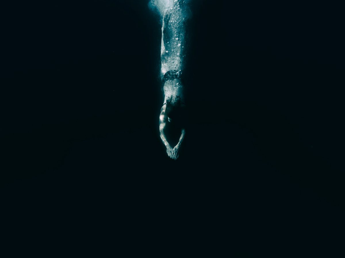 An anonymous woman diving into the water at night.