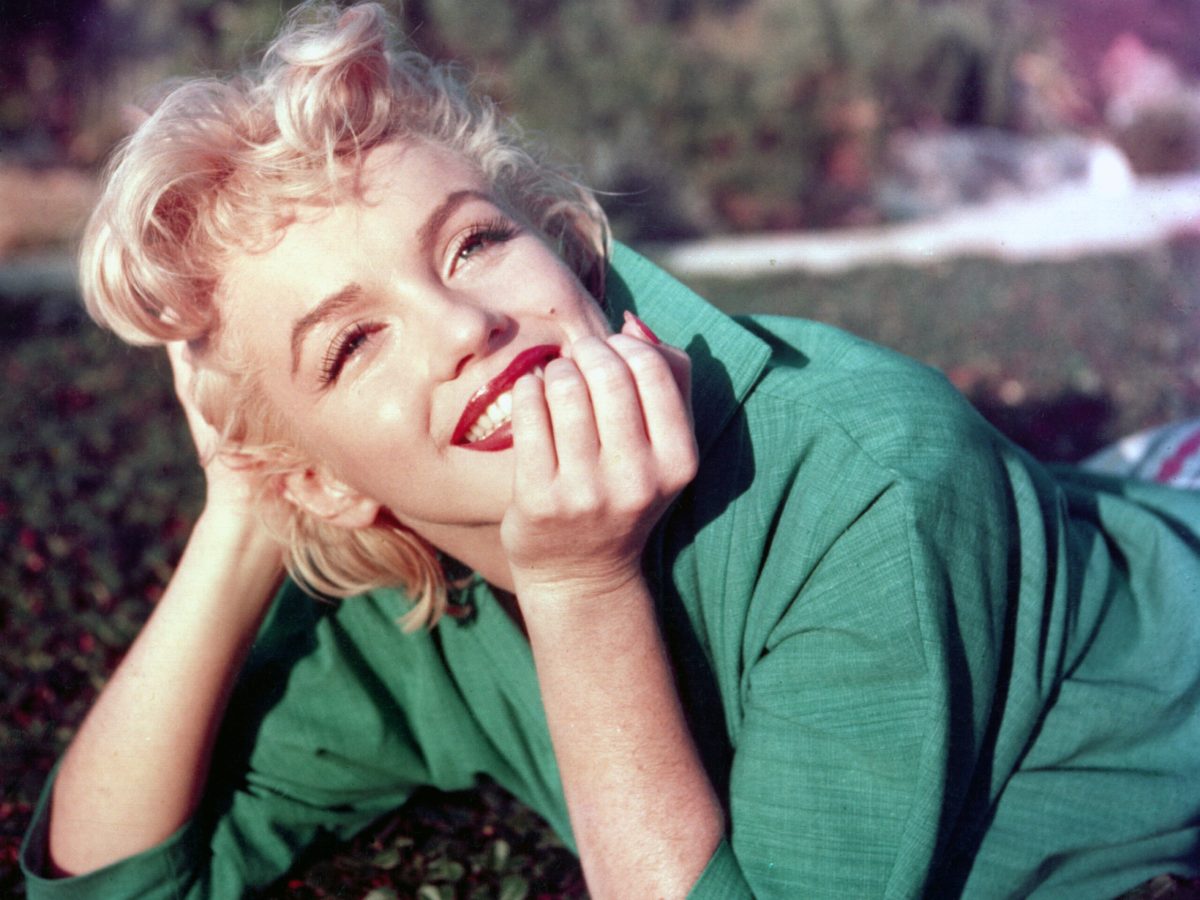 Marilyn Monroe laying on a lawn smiling