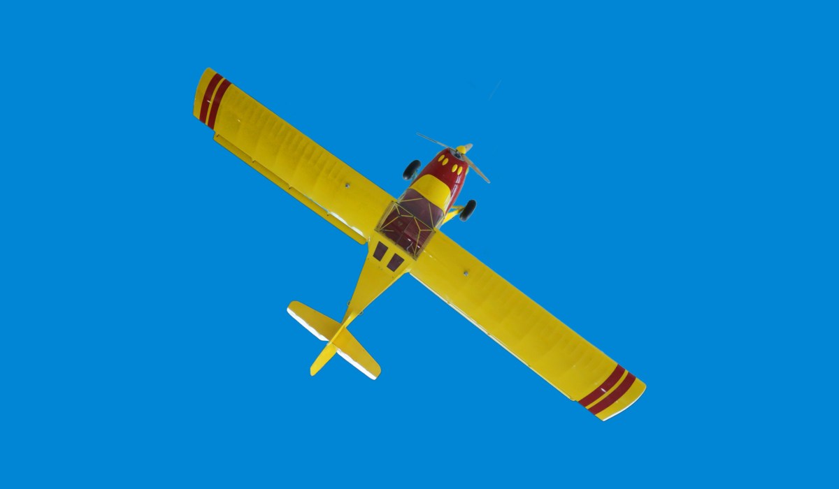 A bright yellow stunt plane on a sky-like blue background