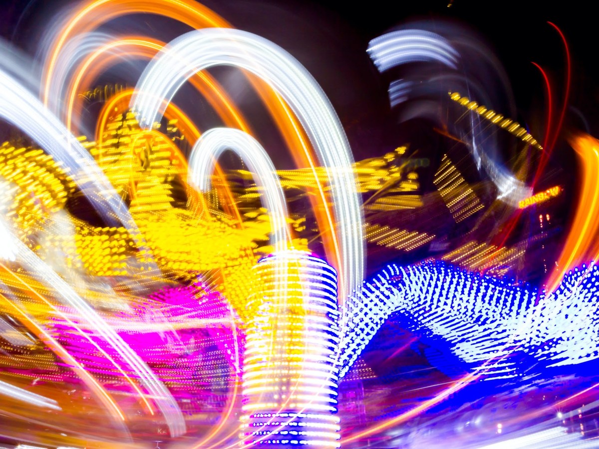 Blurry neon lights and light trails of moving carnival rides at right