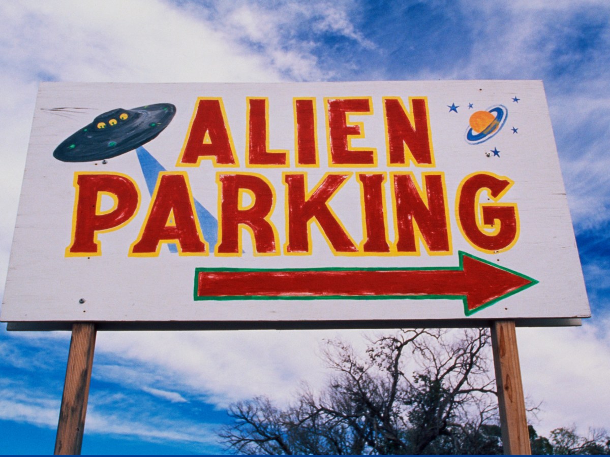 A billboard with a drawing of a UFO and the words ALIEN PARKING, with an arrow