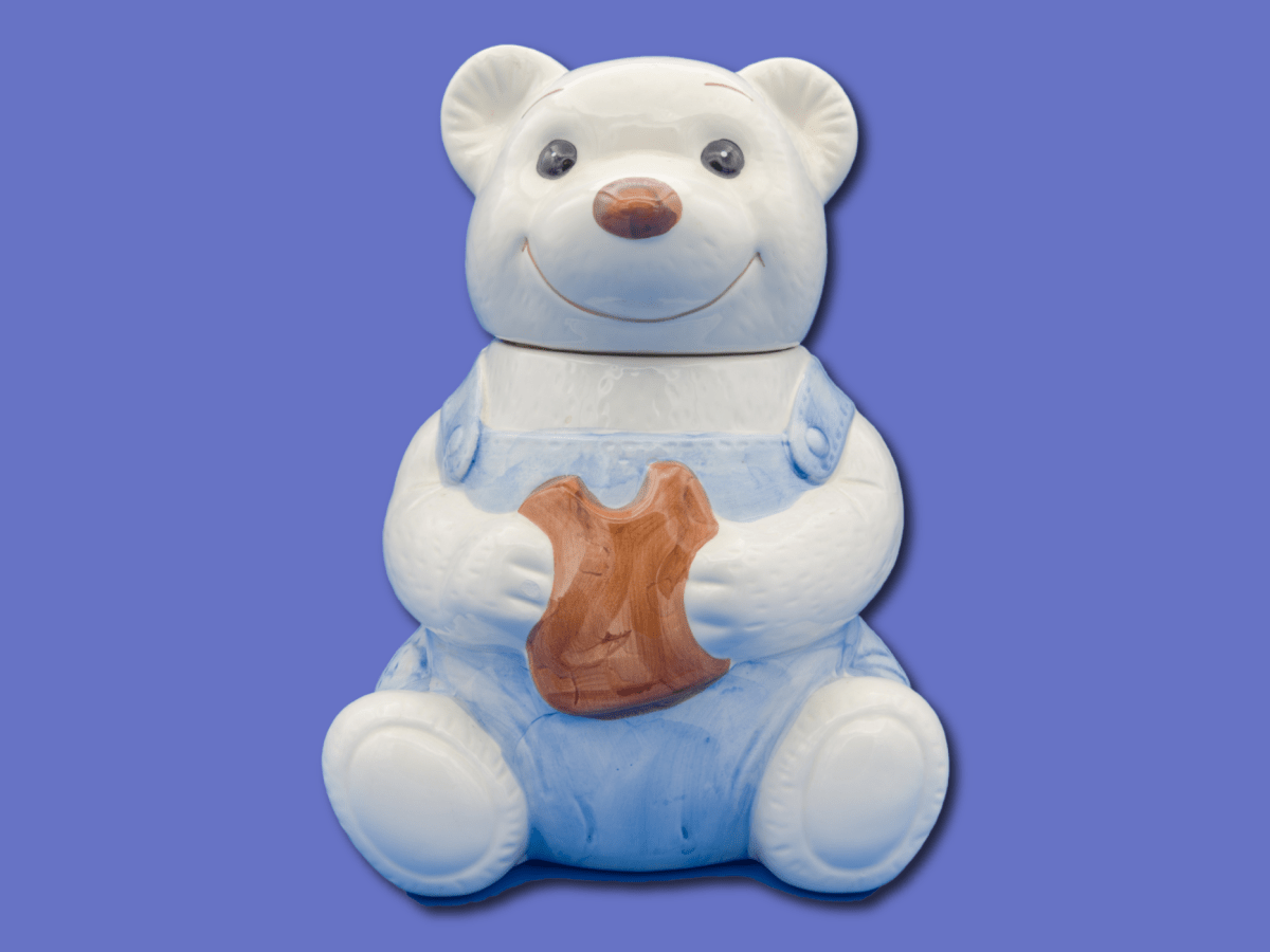 A blue and white bear-shaped ceramic cookie jar with a slightly creepy grin.