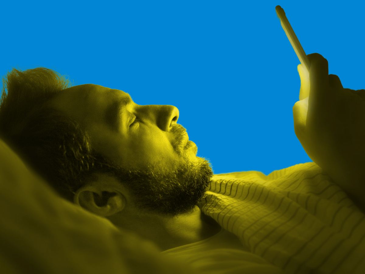 a man on his phone lying down in bed