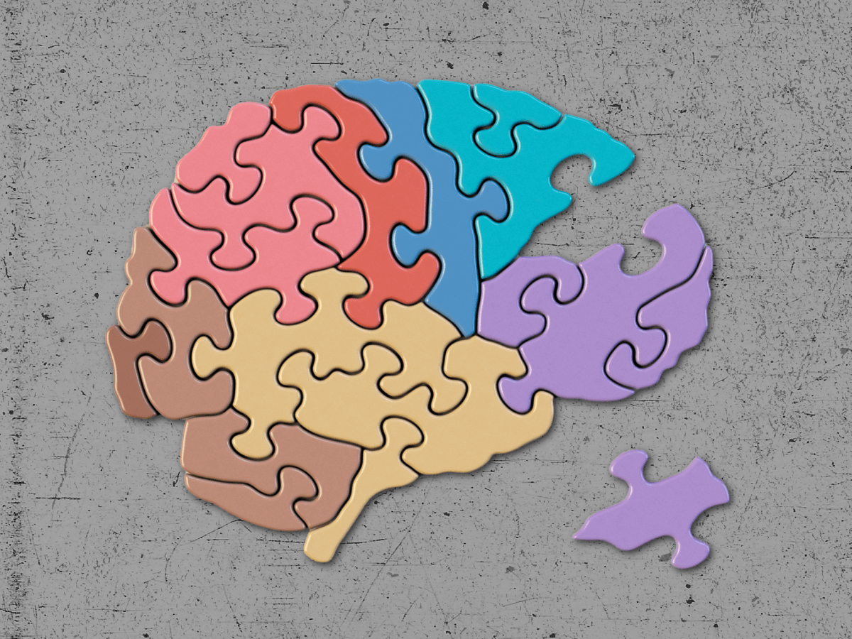 Abstract illustration of a brain against a textured gray background. The brain is made up of pastel-colored puzzle pieces, with one piece separated.