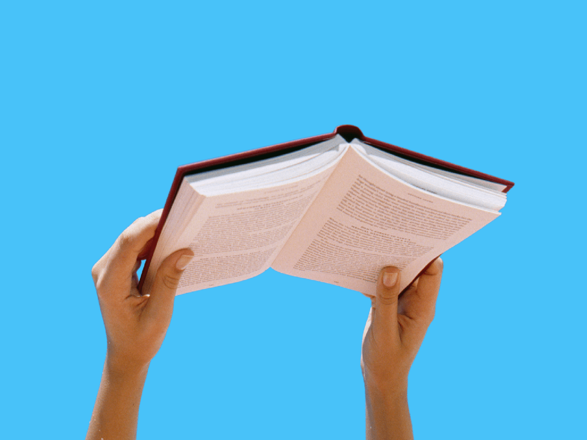 An illustration with a pair of hands holding a book against a blue background.