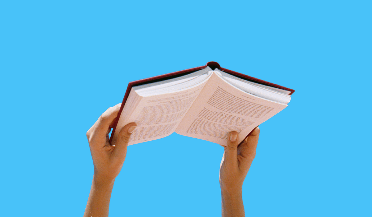 An illustration with a pair of hands holding a book against a blue background.